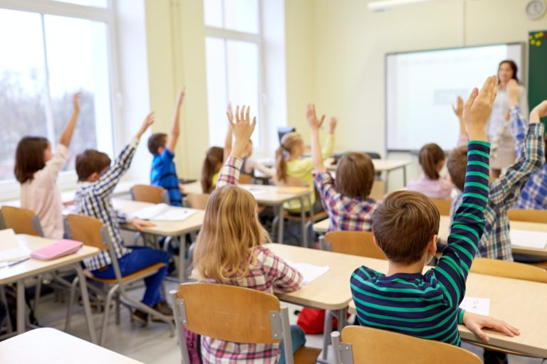 group-of-school-kids-raising-hands-in-classroom.jpg